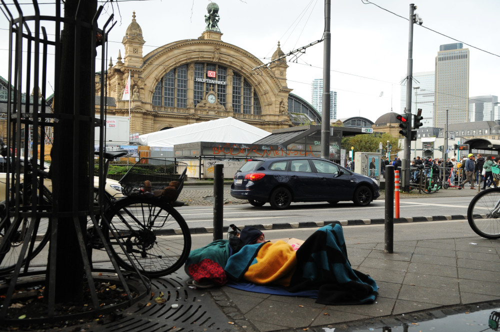 Frankfurt - The daily war for crack and heroin at the train central station district - A frequent situation around the district. A drug adict sleeping "on the road", in front of the Frankfurt central station, beginning of Kaiserstrasse...Undisturbed by the passage of cars.. pedestrian and trams 